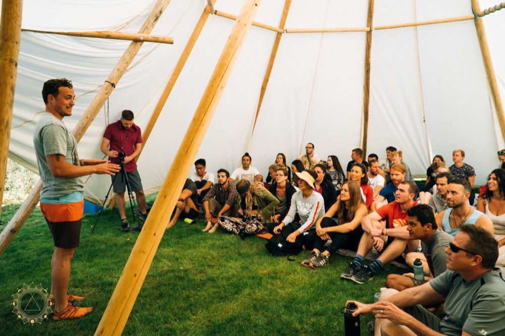 Group seated inside a canvas tent listening to a speaker
