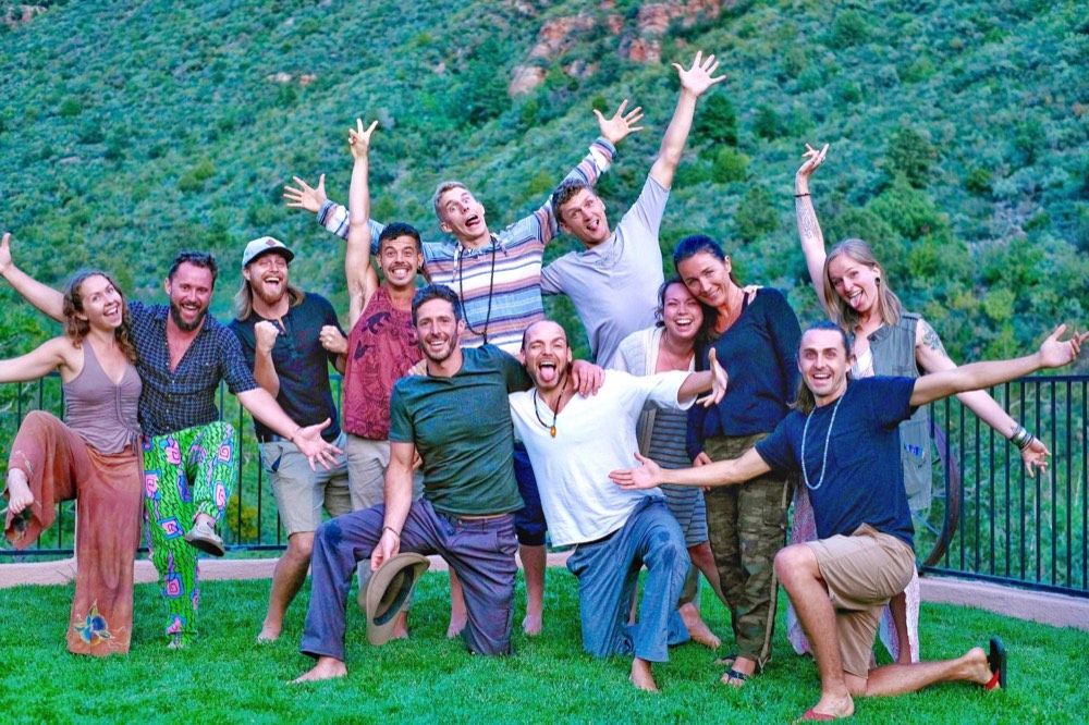 Friends cheering together on a grassy hillside overlooking mountains
